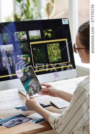 Female Travel Photographer Holding Picture at desk 67370156