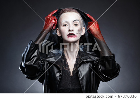 Woman in black leather raincoat taking off hood 67370336