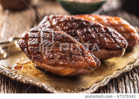 Crispy grilled duck breasts resting on a vintage 67370342