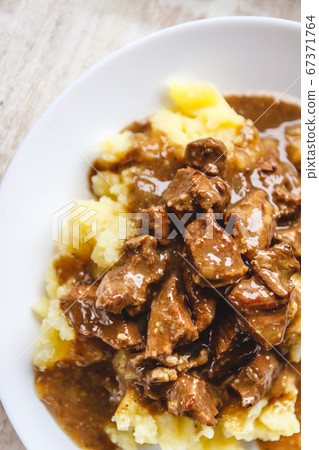 Braised beef, beef stroganoff with gravy on mashed potatoes. Close-up, top view. Braised beef, beef stroganoff with gravy on mashed potatoes. Close-up, top view. 67371764