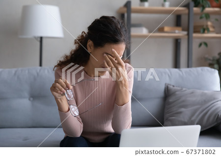Tired young woman rub eyes suffering from migraine Tired young woman rub eyes suffering from migraine 67371802
