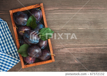 Freash plums in wooden box on wood table top view 67372132