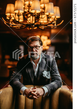 Bearded businessman thinks about important while sitting in leather armchair. Bearded businessman thinks about important while sitting in leather armchair. 67372271