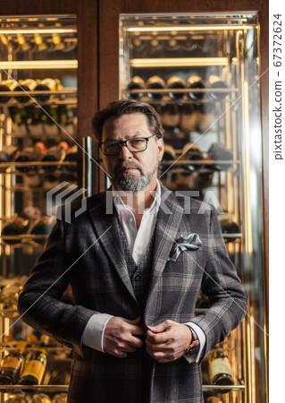 Confident restaurant owner standing against wine cabinet Confident restaurant owner standing against wine cabinet 67372624