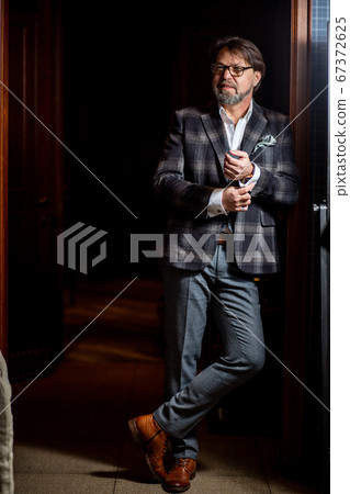 Confident restaurant owner standing against wine cabinet Confident restaurant owner standing against wine cabinet 67372625
