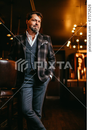 Confident restaurant owner standing against wine cabinet Confident restaurant owner standing against wine cabinet 67372626