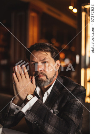 Bearded businessman thinks about important while sitting in leather armchair. Bearded businessman thinks about important while sitting in leather armchair. 67372628