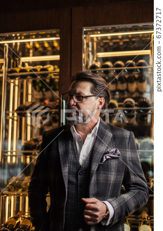 Confident restaurant owner standing against wine cabinet Confident restaurant owner standing against wine cabinet 67372717