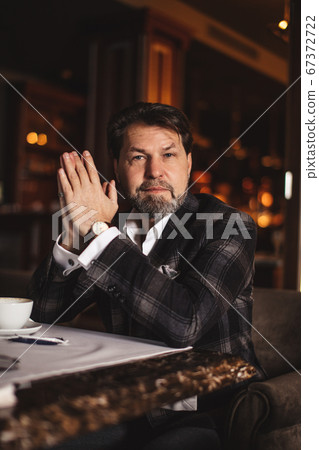 Bearded businessman thinks about important while sitting in leather armchair. Bearded businessman thinks about important while sitting in leather armchair. 67372722