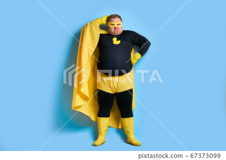 thoughtful fat superhero isolated over blue background thoughtful fat superhero isolated over blue background 67373099