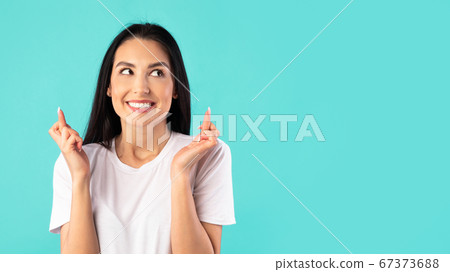 Hopeful beautiful young girl crossing her fingers Hopeful beautiful young girl crossing her fingers 67373688