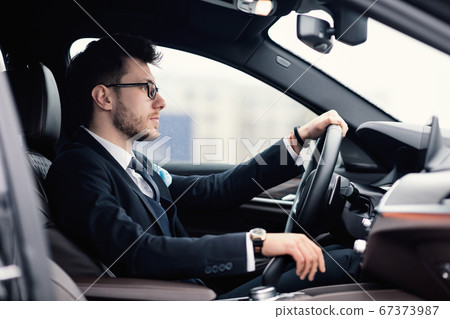 Young business man driving alone in his new car 67373987