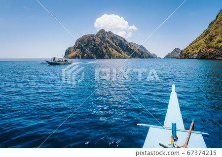 El Nido, Philippines. Front of Island hopping Tour boat hover over open strait between exotic karst limestone islands on travel tour trip El Nido, Philippines. Front of Island hopping Tour boat hover over open strait between exotic karst limestone islands on travel tour trip 67374215