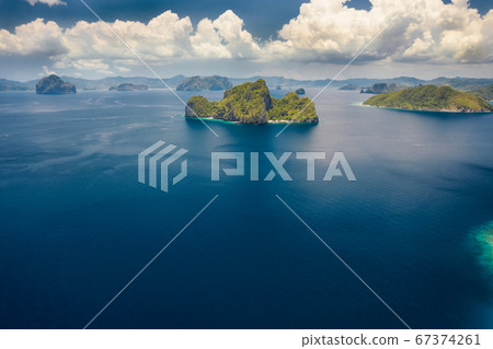 Aerial view the Entalula Island from the distance. Open ocean, white clouds at high altitude. Bacuit Bay, El Nido, Palawan, Philippines 67374261