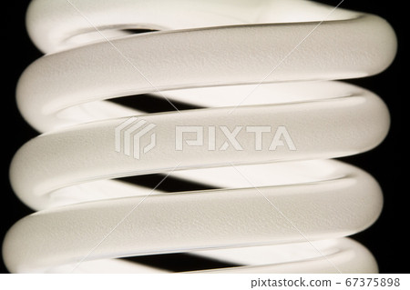 Fluorescent light bulb isolated on black background. Economical home lighting. Energy saving concept. Fluorescent light bulb isolated on black background. Economical home lighting. Energy saving concept. 67375898