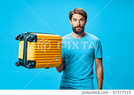 A guy with a suitcase in his hand looks at the camera A guy with a suitcase in his hand looks at the camera 67377519