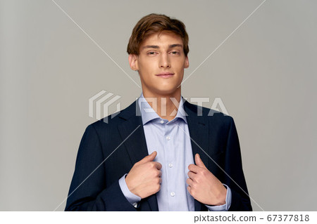 Happy man in a blue shirt straightens his jacket and smiles Happy man in a blue shirt straightens his jacket and smiles 67377818