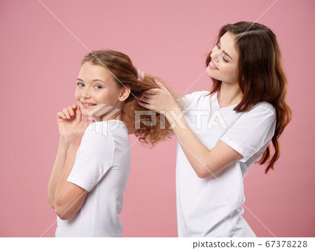 Happy woman does a hairdress to a little daughter  67378228