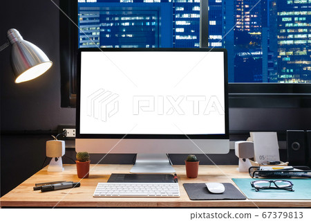 Graphic designer's workspace with city night view 67379813