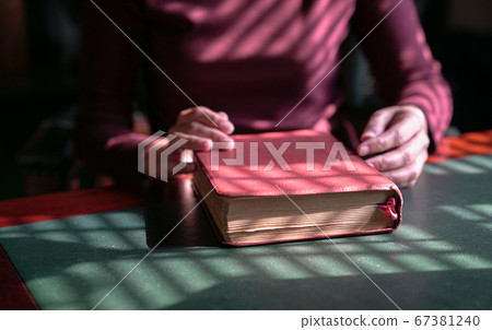 Woman's hands on a closed bible on a table 67381240