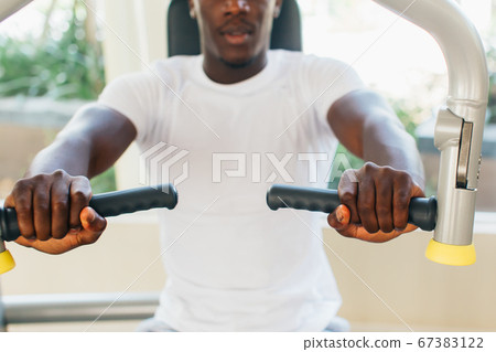 African American athlete doing exercise for chest muscles on pec deck machine during workout in gym African American athlete doing exercise for chest muscles on pec deck machine during workout in gym 67383122