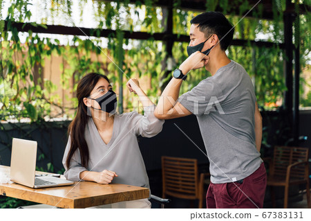 Asian woman and man friends wearing face mask outdoors. Friends greeting and shaking with elbows as new normal. Corona Virus - Covid 19 elbow bumps greeting style to prevent contact and virus spread Asian woman and man friends wearing face mask outdoors. Friends greeting and shaking with elbows as new normal. Corona Virus - Covid 19 elbow bumps greeting style to prevent contact and virus spread 67383131