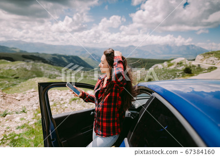 beautiful woman tourist travel by car and browsing smartphone in mountains 67384160