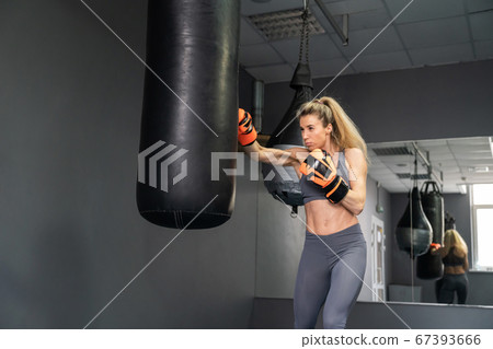 Young woman wearing punching gloves doing boxing training at the gym 67393666