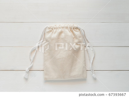 Canvas bag with drawstring, mockup of small eco sack made from natural cotton fabric cloth flat lay on white wood background from top view Canvas bag with drawstring, mockup of small eco sack made from natural cotton fabric cloth flat lay on white wood background from top view 67393667