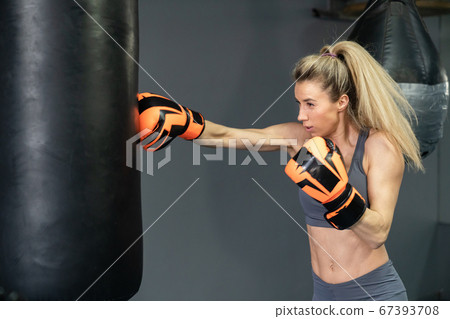 Young woman wearing punching gloves doing boxing training at the gym Young woman wearing punching gloves doing boxing training at the gym 67393708