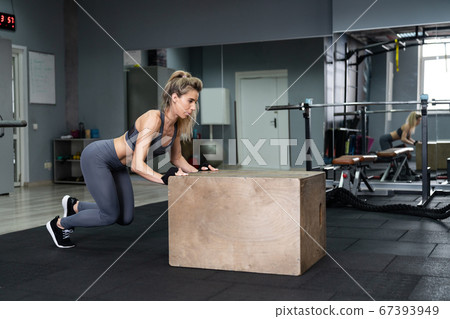 Beautiful young sports woman doing push ups on fit box at gym Beautiful young sports woman doing push ups on fit box at gym 67393949