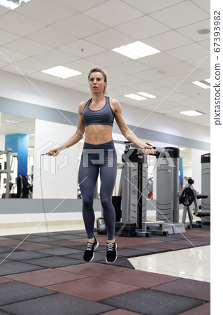 Young woman with jumping rope in fitness center 67393982