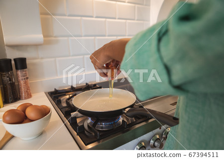Mid section of woman cooking eggs in the kitchen Mid section of woman cooking eggs in the kitchen 67394511