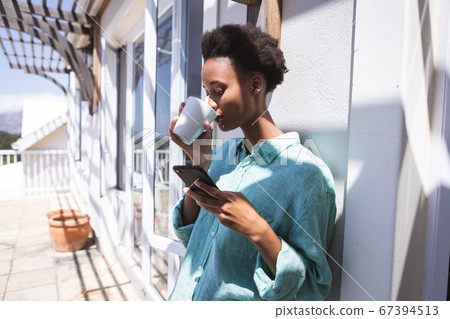 Woman drinking coffee while standing outdoors 67394513