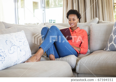 Woman reading book while sitting on the couch 67394551