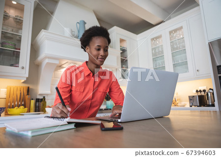 Woman using laptop in the kitchen 67394603