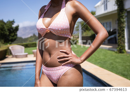 Mid section of woman standing by the pool Mid section of woman standing by the pool 67394613