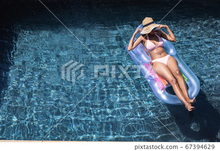 Woman floating on inflatable ring in the pool Woman floating on inflatable ring in the pool 67394629
