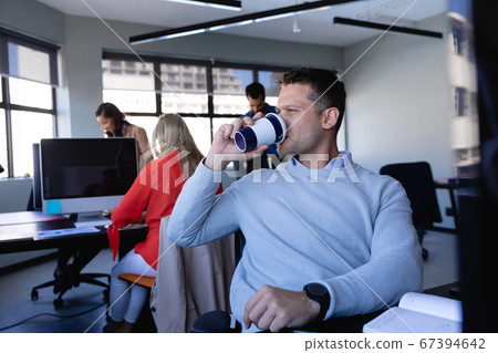 Caucasian man drinking coffee in office 67394642