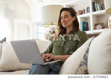 Woman using laptop while sitting on couch at home 67394661