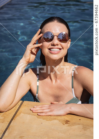 Portrait of woman with sunglasses in the pool 67394662