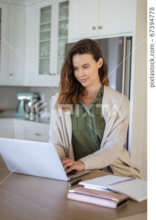 Woman using laptop in the kitchen Woman using laptop in the kitchen 67394778
