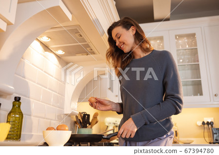 Woman cooking eggs in the kitchen Woman cooking eggs in the kitchen 67394780
