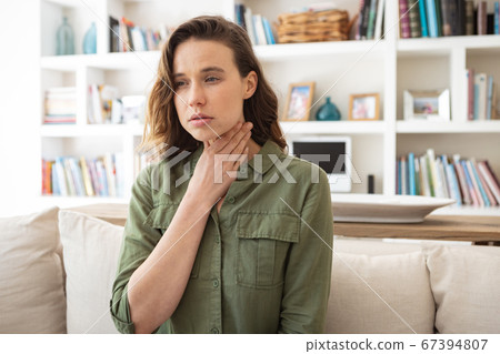 Woman with sore throat holding her neck at home Woman with sore throat holding her neck at home 67394807