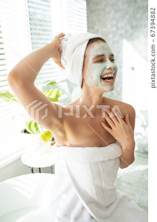 Woman with face pack smiling in bathroom Woman with face pack smiling in bathroom 67394882