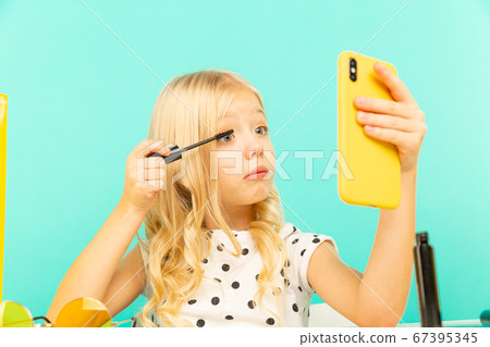 Happy little girl in front of phone camera making video for vlog. Working as blogger, recording video tutorial for Internet. Happy little girl in front of phone camera making video for vlog. Working as blogger, recording video tutorial for Internet. 67395345