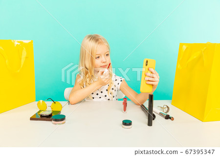 Happy girl at home speaking in front of camera for vlog. Kid working as blogger, recording video tutorial for Internet. Happy girl at home speaking in front of camera for vlog. Kid working as blogger, recording video tutorial for Internet. 67395347