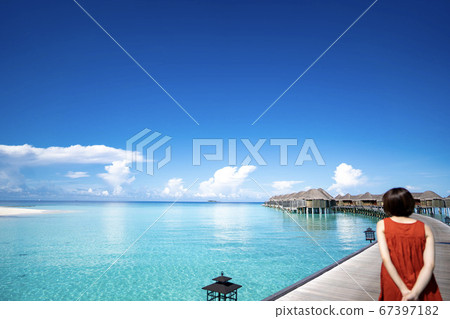 Woman in red dress heading to overwater cottage in Maldives (Pinto cottage) 67397182