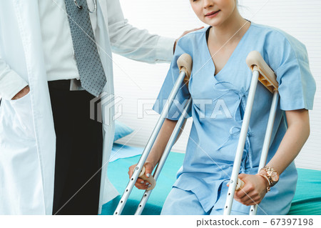 Doctor takes care of patient in crutch at hospital 67397198