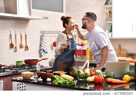 Loving young Asian couple cooking in kitchen making healthy food together 67398505